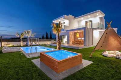 a villa with a swimming pool in front of a house at Martini Villas in Kremasti