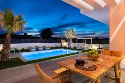 a patio with a table and a swimming pool at Martini Villas in Kremasti