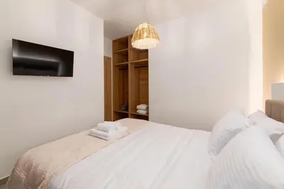 a white bedroom with a bed and a tv at Martini Villas in Kremasti