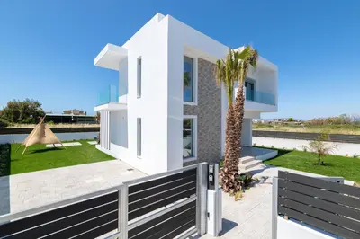 a white house with a palm tree in front of it at Martini Villas in Kremasti