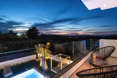 a balcony with chairs and a swimming pool at night at Martini Villas in Kremasti