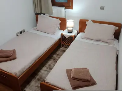 two beds in a bedroom with a lamp on a table at Tsampika's Traditional Stone Cottage in Siana in Siána