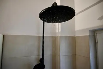 a black shower head hanging from the ceiling in a bathroom at Casa Sym Faliraki in Faliraki