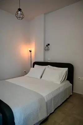 a bedroom with a white bed with two lights on the wall at Casa Sym Faliraki in Faliraki