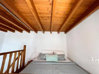 a bed in a room with a wooden ceiling at Ambela House Soroni in Soroni