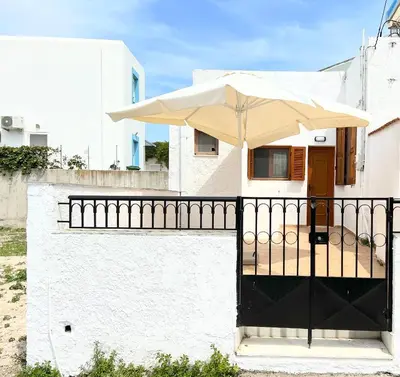 a white house with a black fence and an umbrella at Ambela House Soroni in Soroni