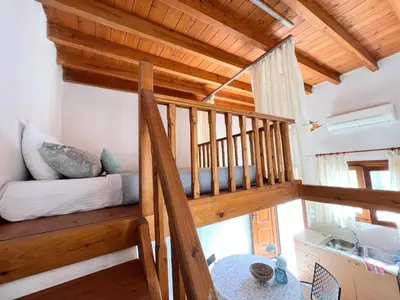 a room with a loft with a bed and a sink at Ambela House Soroni in Soroni