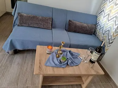 a living room with a blue couch and a table at Lydia's cozy house in Paradeísion