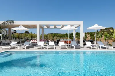 a swimming pool with white chairs and umbrellas at Villa Korali in Pastida