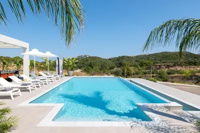 a swimming pool with lounge chairs and a resort at Villa Korali in Pastida