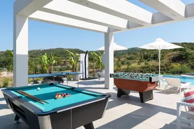 a patio with a pool table and two tables at Villa Korali in Pastida