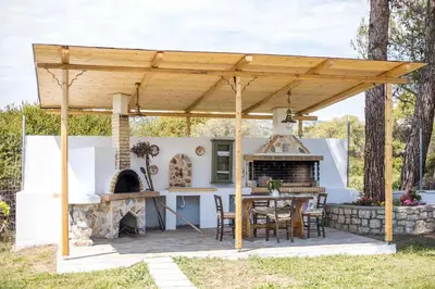 a wooden pergola with a table and a fireplace at Petrino Eco Conscious Living in Kalithies