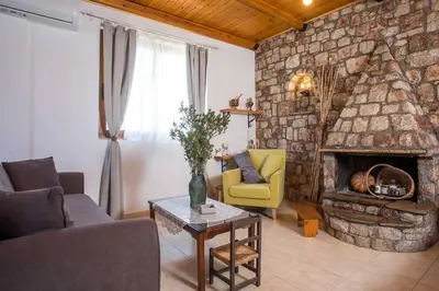 a living room with a couch and a stone fireplace at Petrino Eco Conscious Living in Kalithies