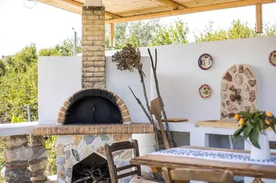 a patio with a stone fireplace and a table at Petrino Eco Conscious Living in Kalithies