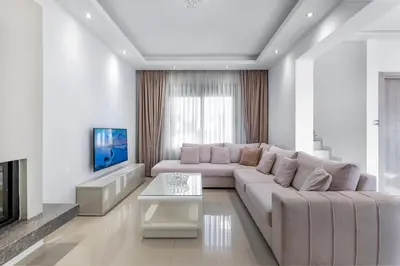 a white living room with a couch and a tv at Villa Marina in Ialyssos