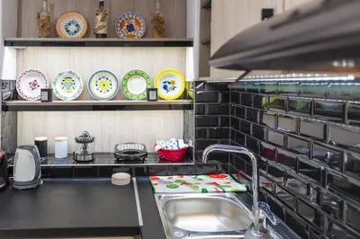 a kitchen with a sink and plates on a shelf at (Stoa escape) traditional home in Archangelos