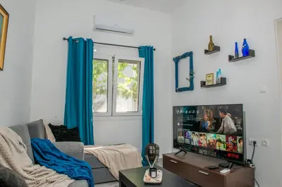 a living room with a tv and blue curtains at (Stoa escape) traditional home in Archangelos