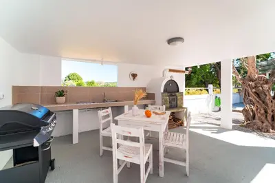 a kitchen with a table and chairs and a grill at Ixian Bliss Pool Villa in Ialyssos