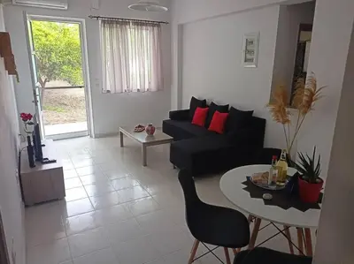 a living room with a black couch and a table at Hibiscus Green Appartments 1 in Afantou