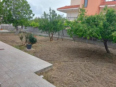 a yard with trees in front of a building at Hibiscus Green Appartments 1 in Afantou