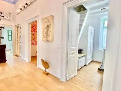 an open hallway with white walls and wood floors and a painting at “Athenas” Neoclassic Harbour View Apartment in Symi