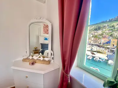a mirror on a dresser next to a window at “Athenas” Neoclassic Harbour View Apartment in Symi