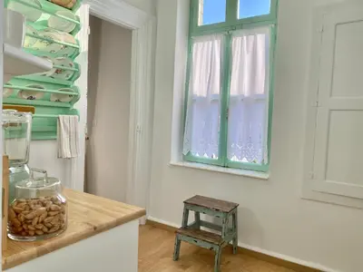 a kitchen with a counter with a window and a stool at “Athenas” Neoclassic Harbour View Apartment in Symi