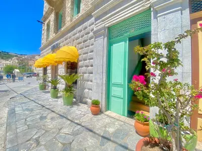 a building with a blue door and potted plants at “Athenas” Neoclassic Harbour View Apartment in Symi