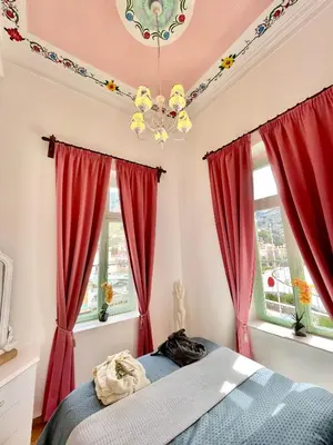 a bedroom with red curtains and a bed at “Athenas” Neoclassic Harbour View Apartment in Symi