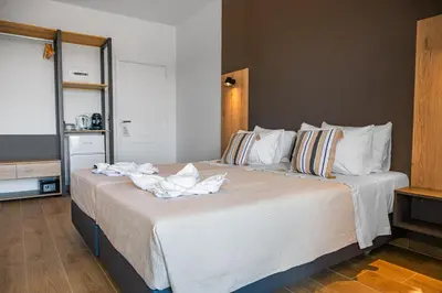 a bedroom with a large bed with white sheets at Eva's Rooms in Faliraki