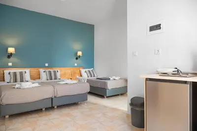 a room with two beds and a blue wall at Eva's Rooms in Faliraki