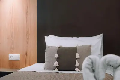 a bedroom with a bed with a pillow and a persons feet at Eva's Rooms in Faliraki