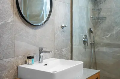 a bathroom with a sink and a mirror and a shower at Eva's Rooms in Faliraki