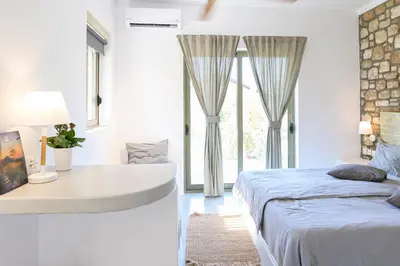 a bedroom with a bed and a desk and windows at LOGOS Beach Village in Theologos