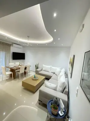 a living room with a white couch and a table at The Cosy Nest -BREAKFAST INCLUDED & CAR RENTAL AVAILABLE in Rhodes Town