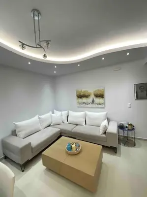 a living room with a white couch and a table at The Cosy Nest -BREAKFAST INCLUDED & CAR RENTAL AVAILABLE in Rhodes Town