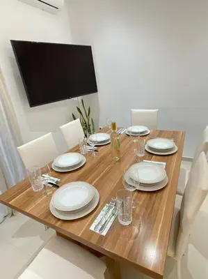 a wooden table with white plates and glasses on it at The Cosy Nest -BREAKFAST INCLUDED & CAR RENTAL AVAILABLE in Rhodes Town